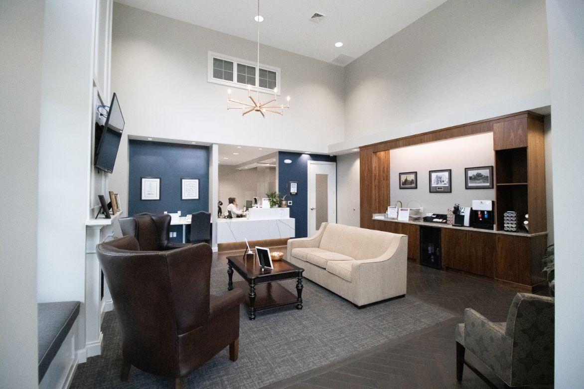 The image shows an interior space with a modern lobby design, featuring a comfortable seating area, a reception desk, and a cozy waiting room atmosphere.