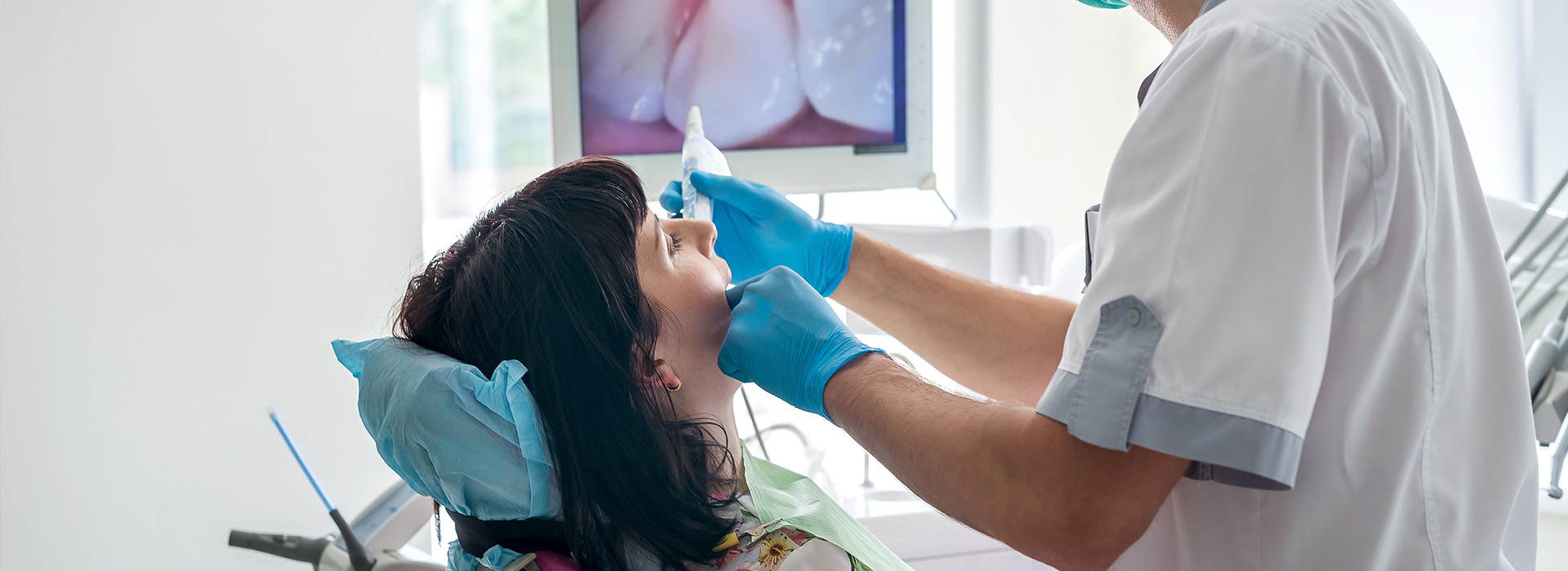 A dental professional performing a procedure on a patient s mouth in an office setting.