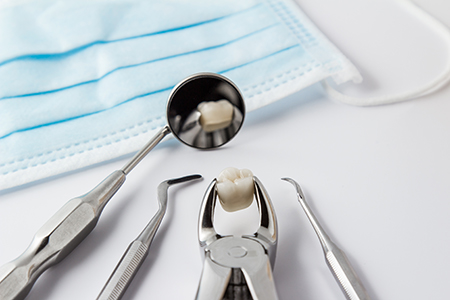 The image shows dental instruments on a white surface with a blue surgical drape in the background.